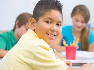 Middle-school-boy | MiddleWeb Smiling boy in a classroom foreground with classmates at desks in the background.